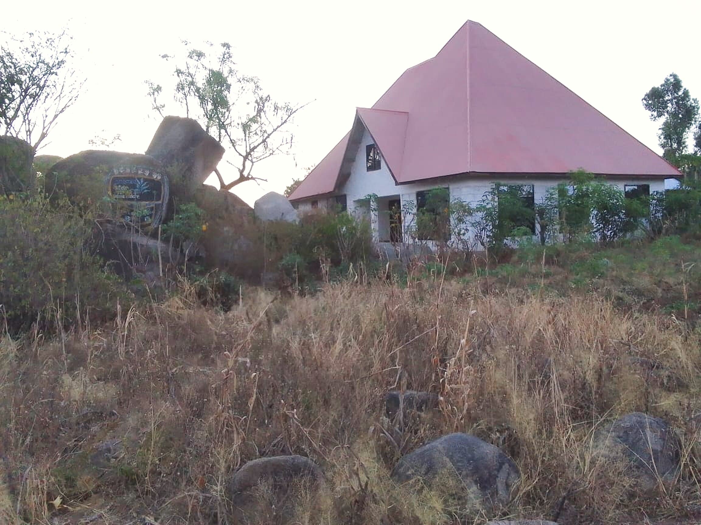 Originalfoto aus Mwanza: das Haus von Hand in Hand mit rotem Dach und unverputzten Steinwänden auf dem Felshügel